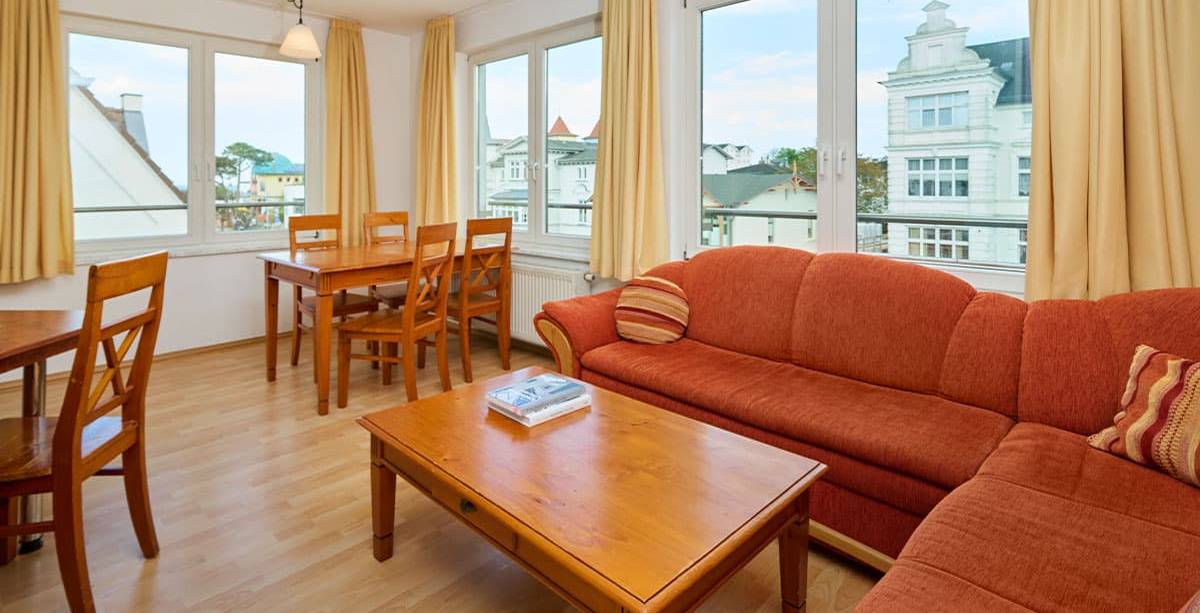 Heller Wohnbereich mit Ecksofa, Couchtisch und Essplatz in den Ferienwohnungen der Schöner Inseln auf Usedom.