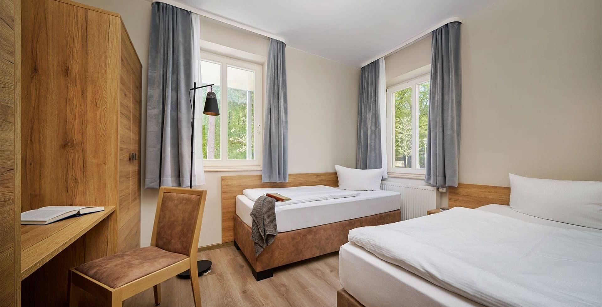 Schlafzimmer mit Doppelbett, Sessel und Fenster in der Familiensuite zur Landseite auf Usedom.