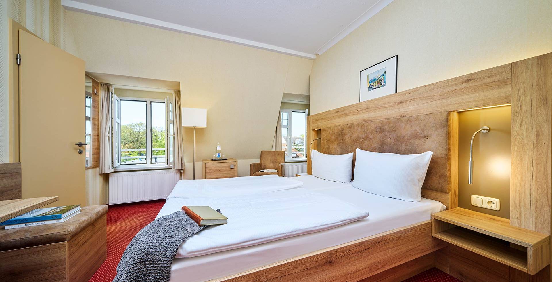 Helles Doppelzimmer mit gemütlicher Sitzecke im Strandhotel Garni Kormoran an der Ostsee.