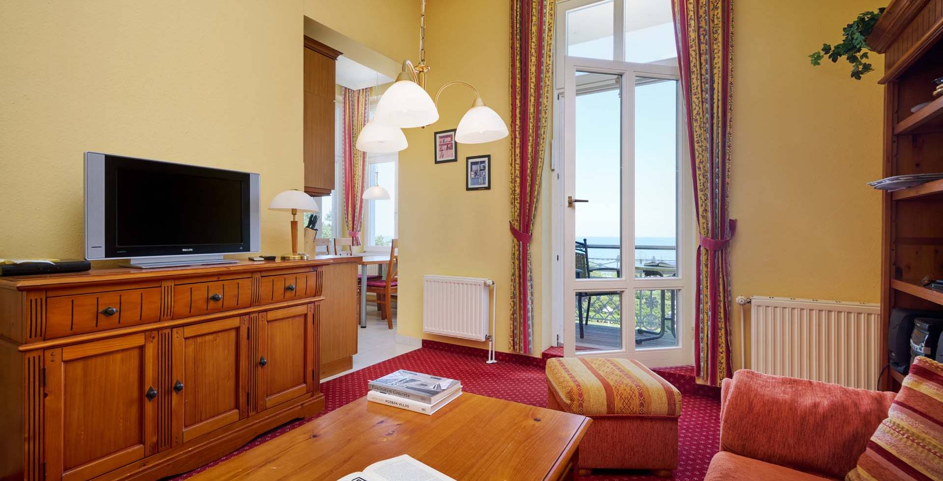 Wohnbereich mit TV, Sessel und Balkon mit Blick auf die Ostsee in den Strandvillen Wald und See auf Usedom.