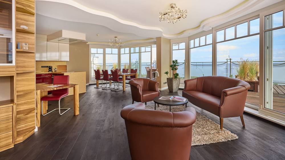 Gesamter Wohnbereich des Penthouses im Strandhotel Prinz von Preussen mit Glastüren, Holzboden, Ledersesseln und Ostseeblick.