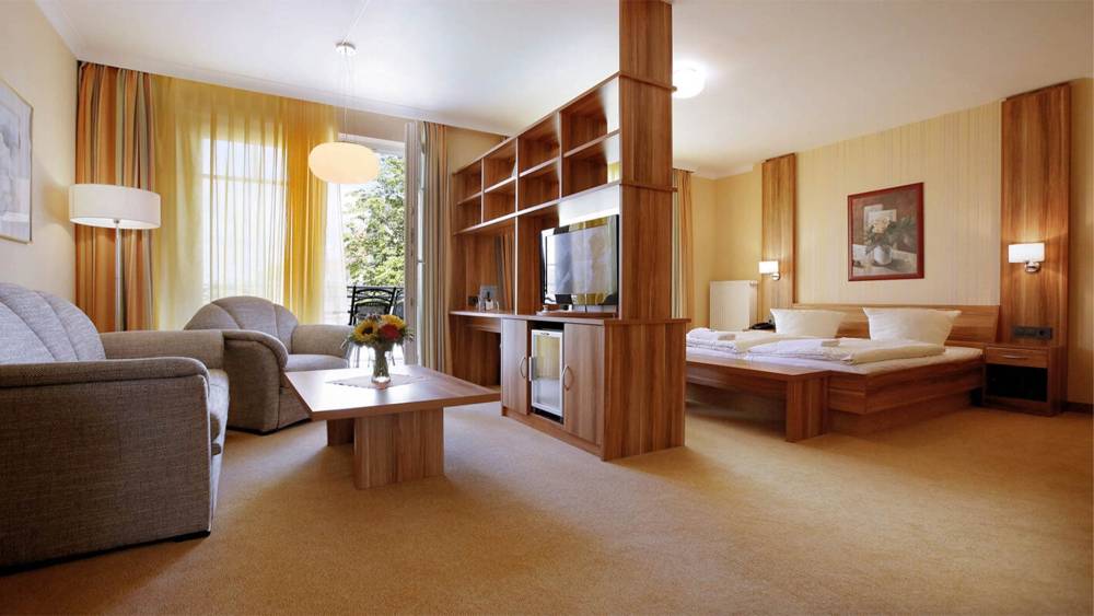 Doppelzimmer im Strandhotel Kormoran auf Usedom mit Wohnbereich, Fernseher, Tisch und Balkon zur Landseite.