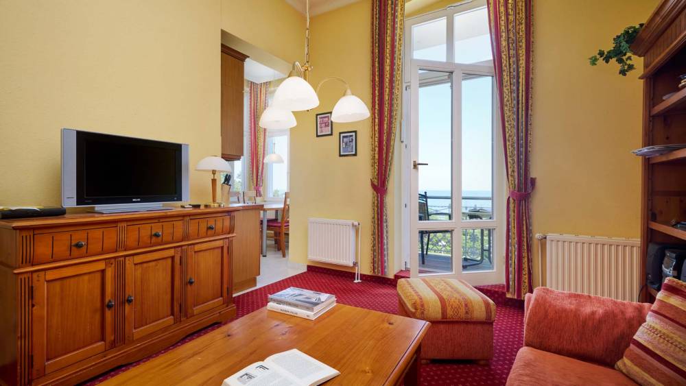 Wohnbereich mit TV, Sessel und Balkon mit Blick auf die Ostsee in den Strandvillen Wald und See auf Usedom.