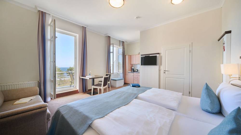Helles Studio Apartment mit Doppelbett, Sofa, Küchenzeile und Meerblick vom Balkon im Strandpalais in Zinnowitz.