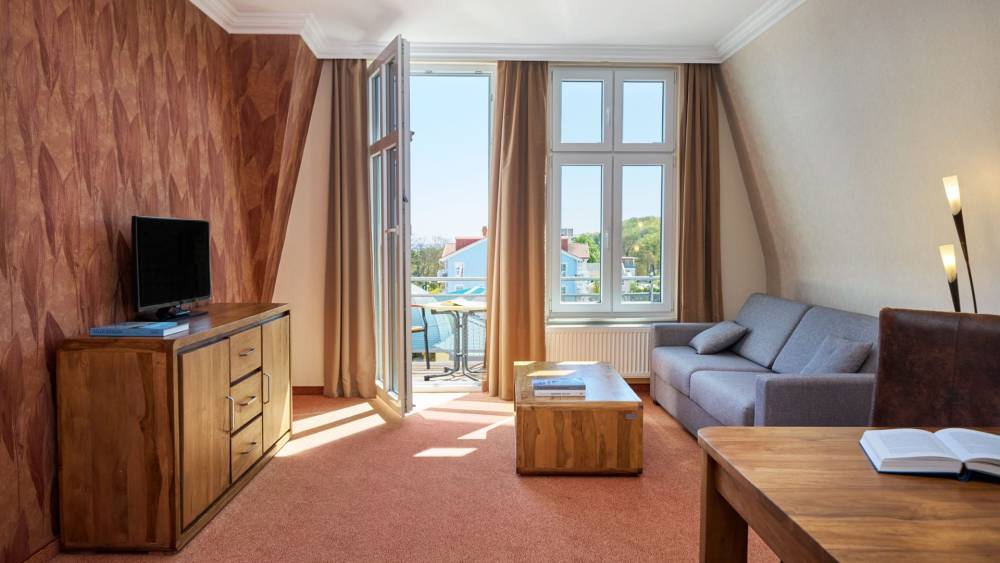 Juniorsuite im Strandhotel Preußenhof mit Sofa, TV, Schreibtisch, Meerblick und Balkon.