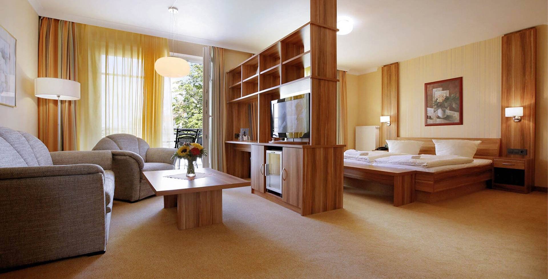 Doppelzimmer im Strandhotel Kormoran auf Usedom mit Wohnbereich, Fernseher, Tisch und Balkon zur Landseite.