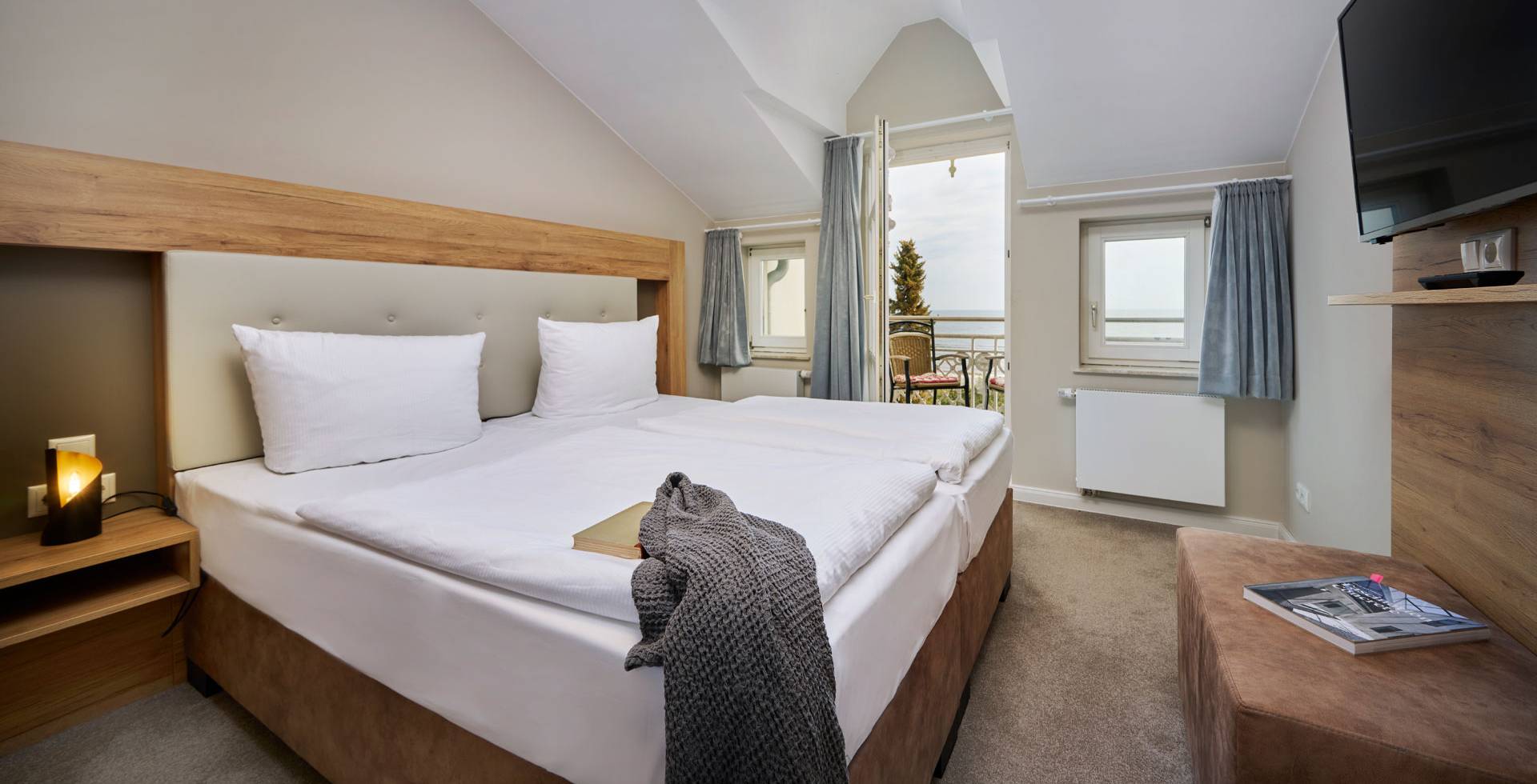 Schlafzimmer mit Doppelbett, TV und Balkonzugang in der Juniorsuite mit Panorama-Meerblick auf Usedom.