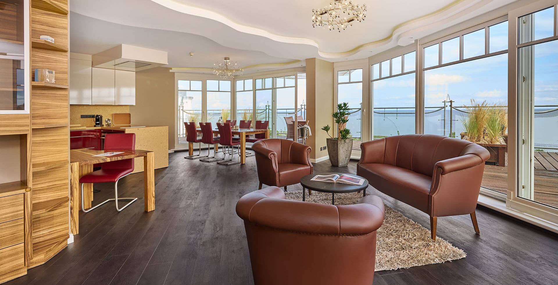 Gesamter Wohnbereich des Penthouses im Strandhotel Prinz von Preussen mit Glastüren, Holzboden, Ledersesseln und Ostseeblick.