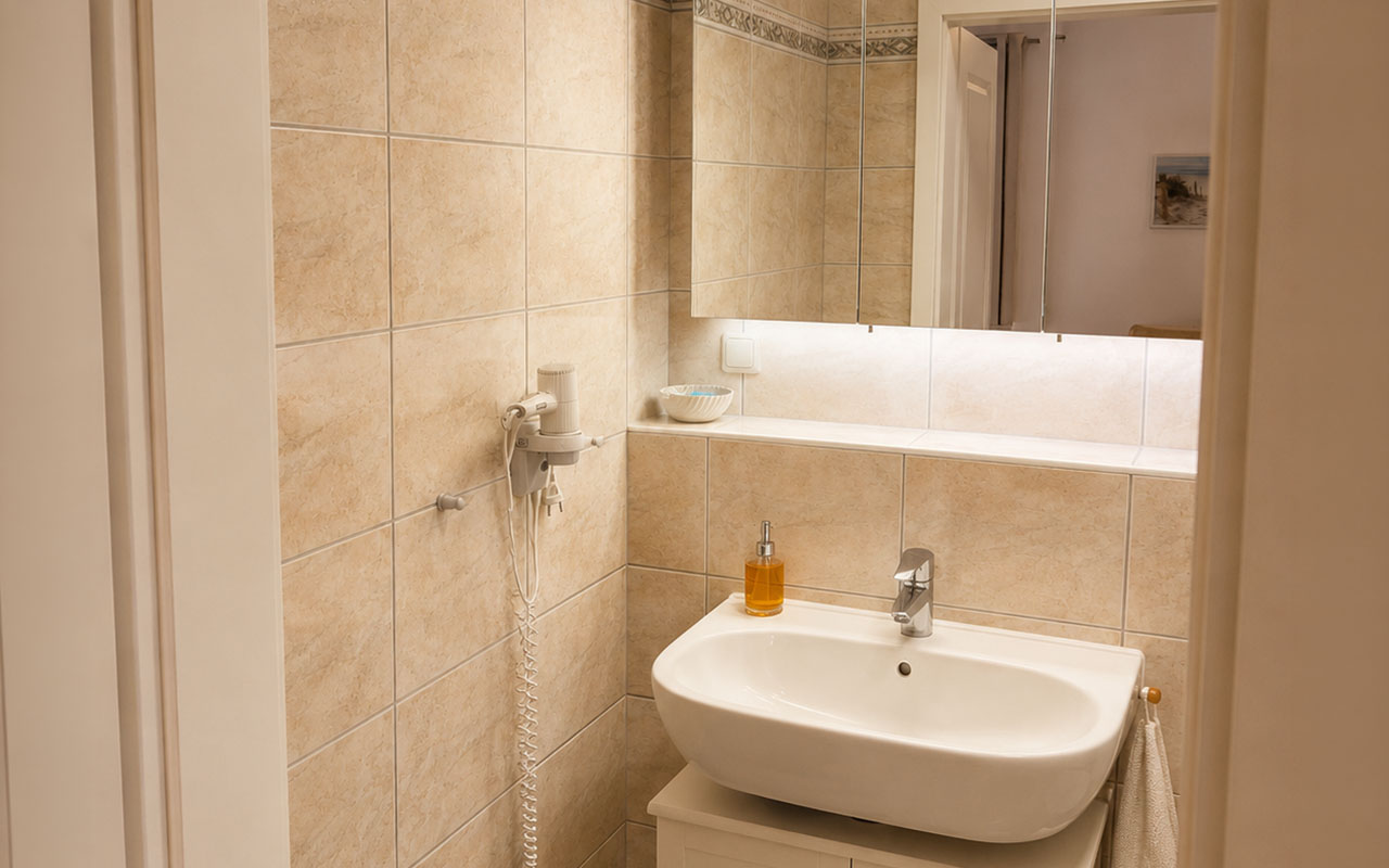 Modernes Badezimmer mit Waschbecken, Spiegelschrank und Föhn in den Strandvillen Wald & See in Zinnowitz.