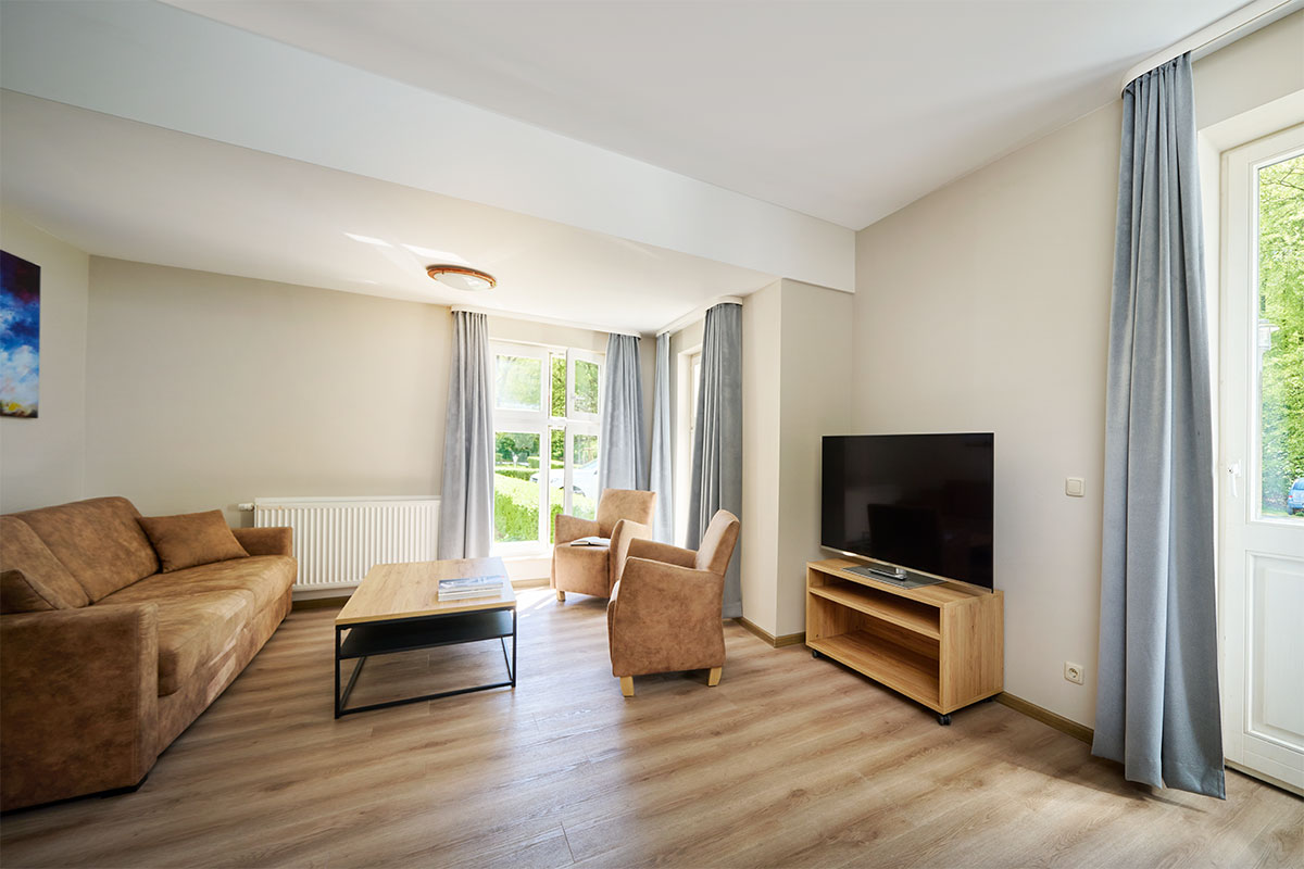 Moderner Wohnbereich mit Sofa, Sesseln und TV in einer Familiensuite der Ostseeinsel Usedom.