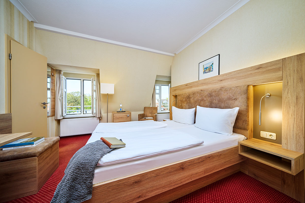 Helles Doppelzimmer mit gemütlicher Sitzecke im Strandhotel Garni Kormoran an der Ostsee.