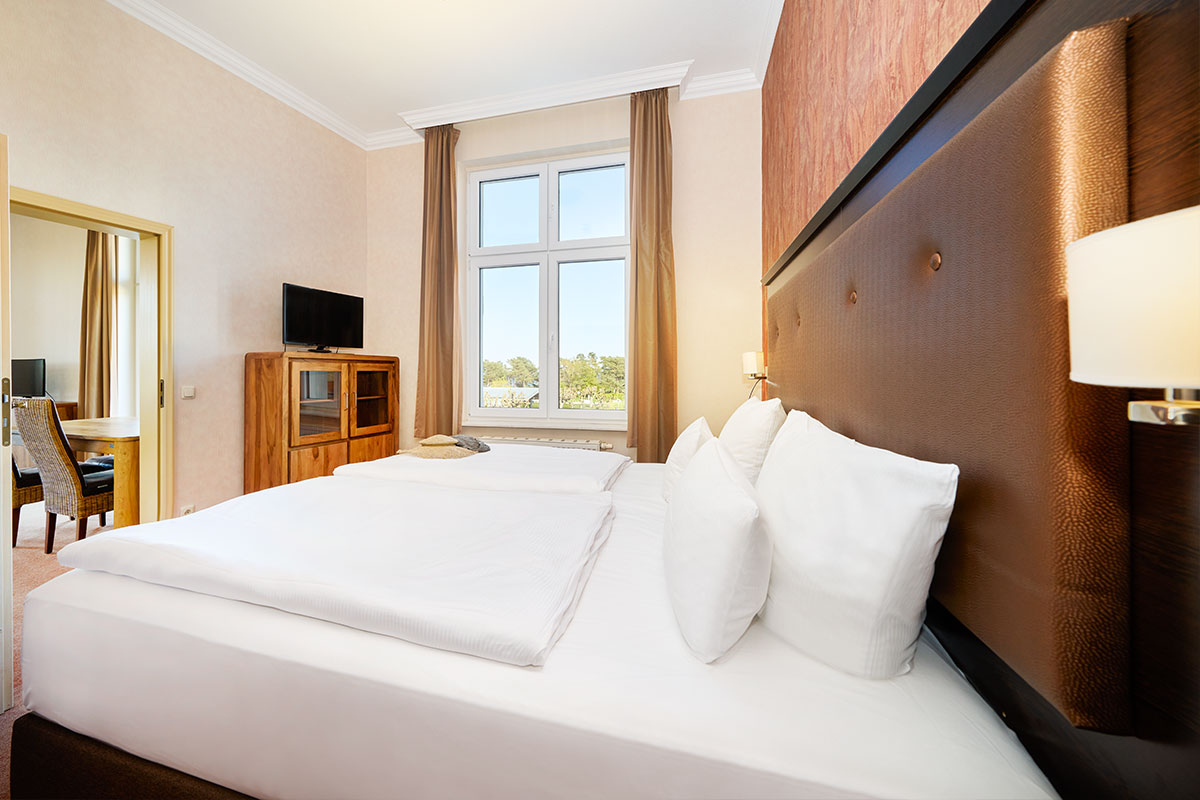 Schlafzimmer mit Doppelbett, TV, Fenster zur Meerseite und Zugang zum Essbereich.