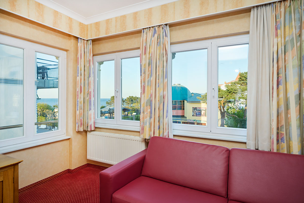 Sitzecke mit Ausblick im Doppelzimmer der Strandvilla Viktoria, Fenster zur Promenade und teilweisem Meerblick.
